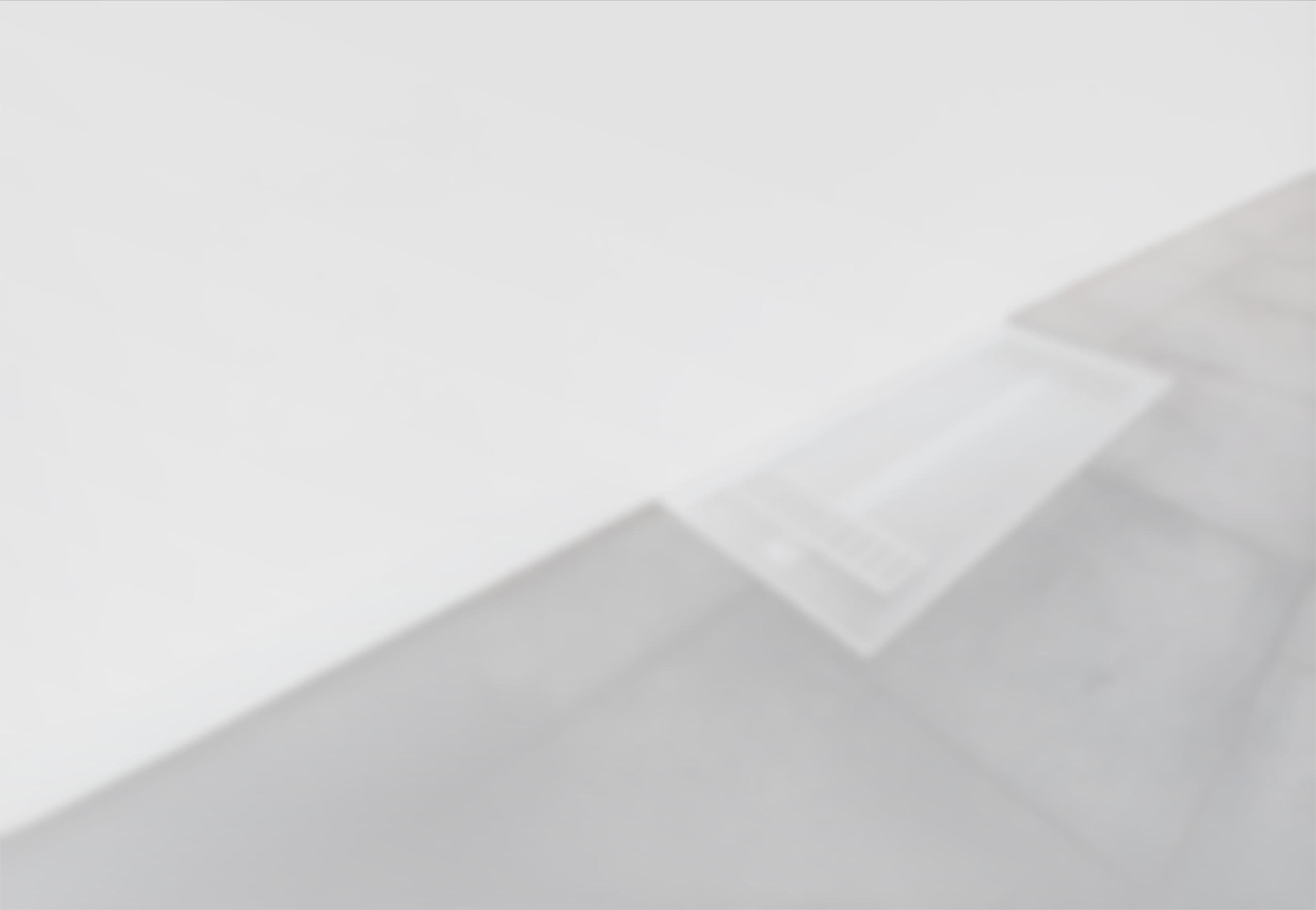 Ein schlichtes, mattiertes Glas-Bodenfenster mit Lüftungsschlitzen neben einer weißen Wand auf dunklen Steinplatten.